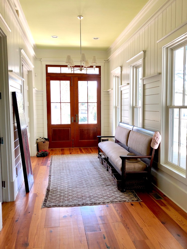 Large beach style medium tone wood floor and brown floor entryway photo in Charleston with white walls and a medium wood front door