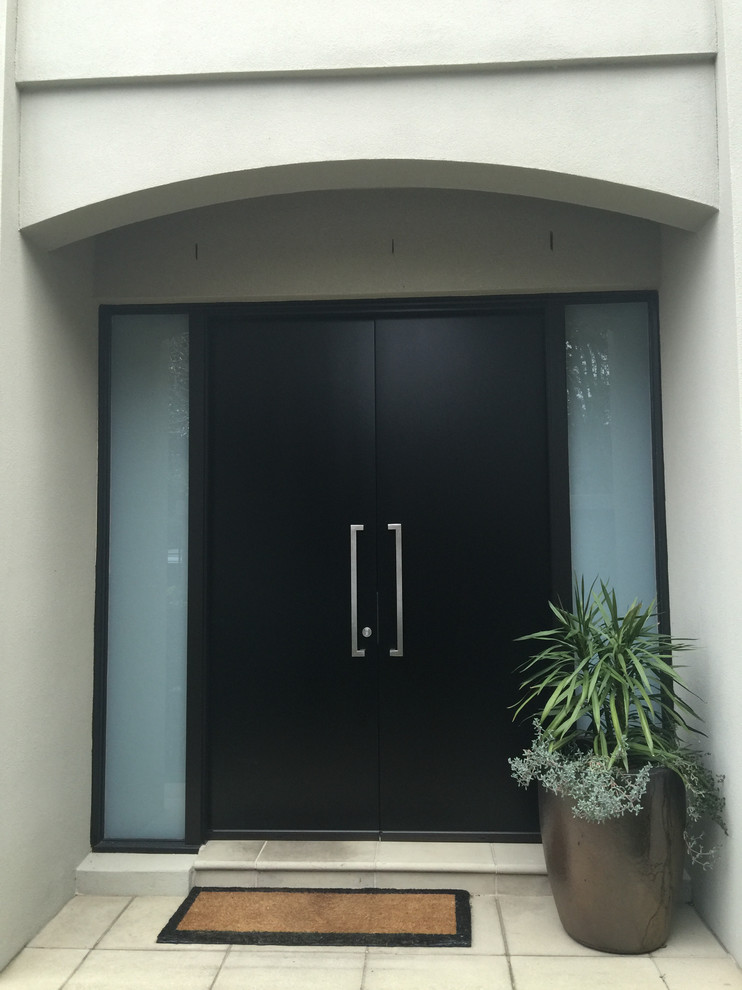 Exempel på en liten modern ingång och ytterdörr, med beige väggar, betonggolv, en dubbeldörr och en svart dörr