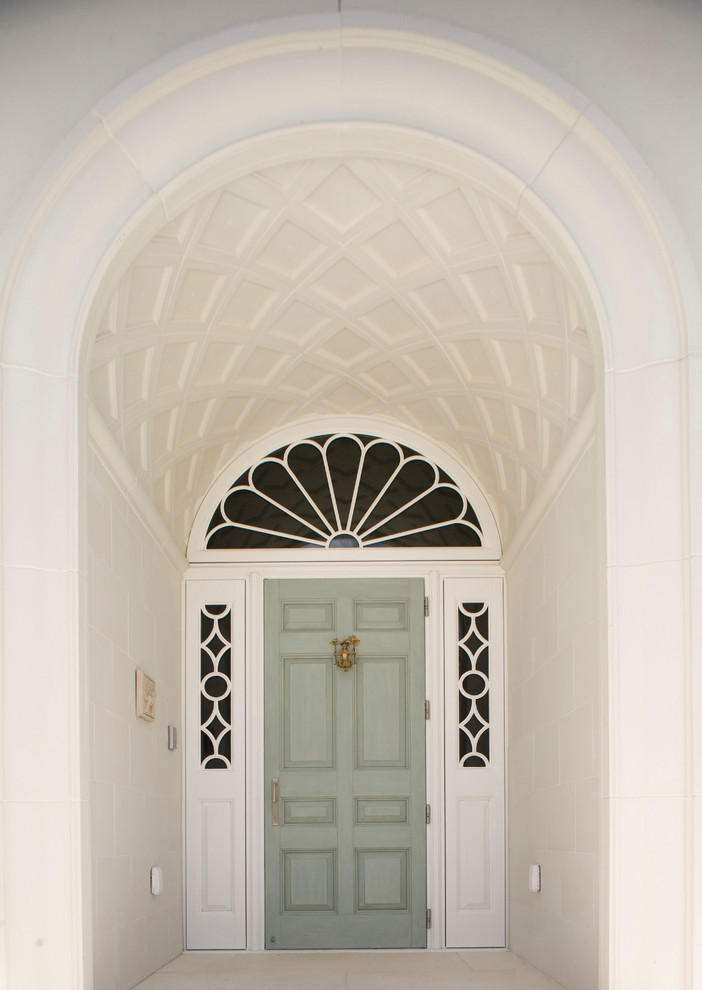 Klassisk inredning av en ingång och ytterdörr, med vita väggar, kalkstensgolv och en enkeldörr