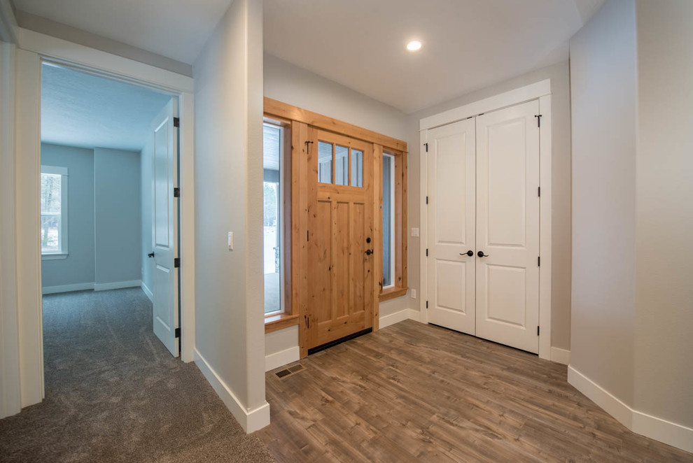 Cette photo montre une porte d'entrée craftsman de taille moyenne avec un mur gris, parquet foncé, une porte simple, une porte en bois brun et un sol marron.