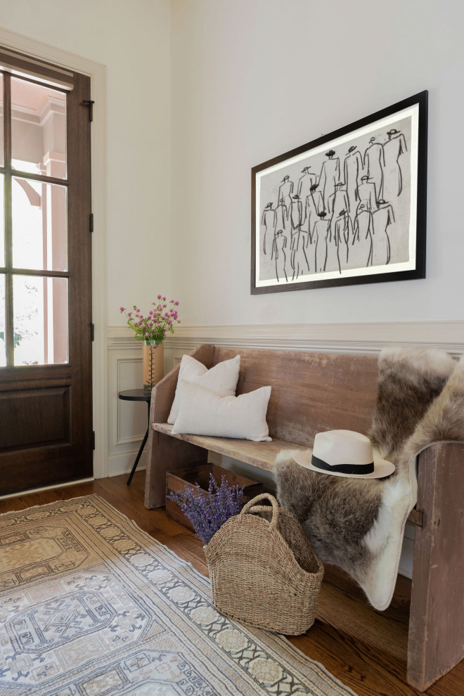 Imagen de entrada clásica renovada con paredes blancas, suelo de madera en tonos medios, puerta simple, puerta de madera oscura, suelo marrón y boiserie