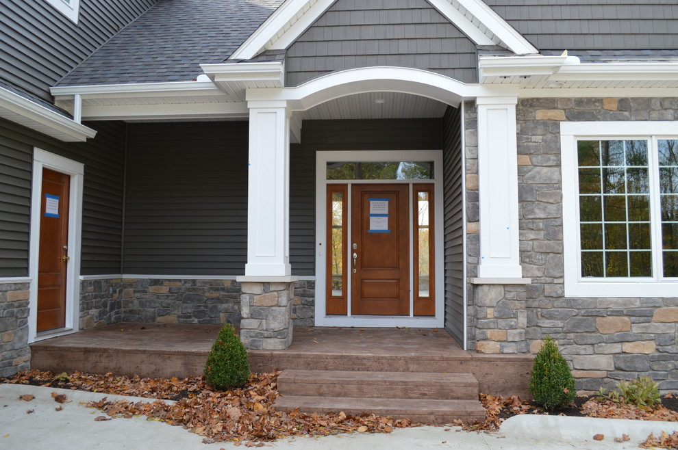 Immagine di una grande porta d'ingresso stile americano con pareti grigie, pavimento in cemento, una porta singola, una porta in legno bruno e pavimento marrone
