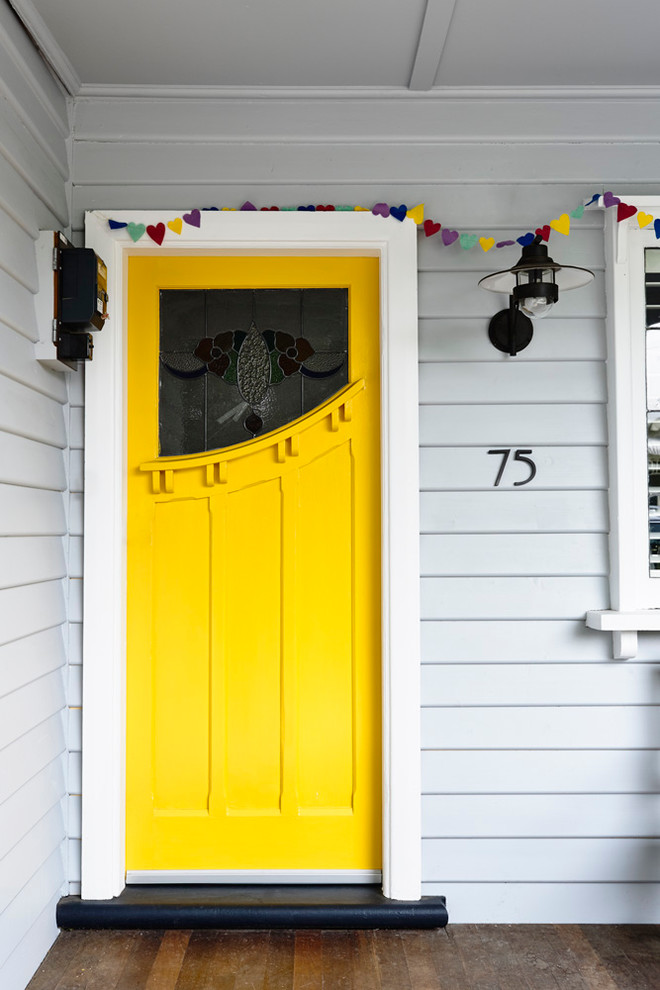 Cette image montre une porte d'entrée design avec un mur blanc, un sol en bois brun, une porte simple et une porte jaune.
