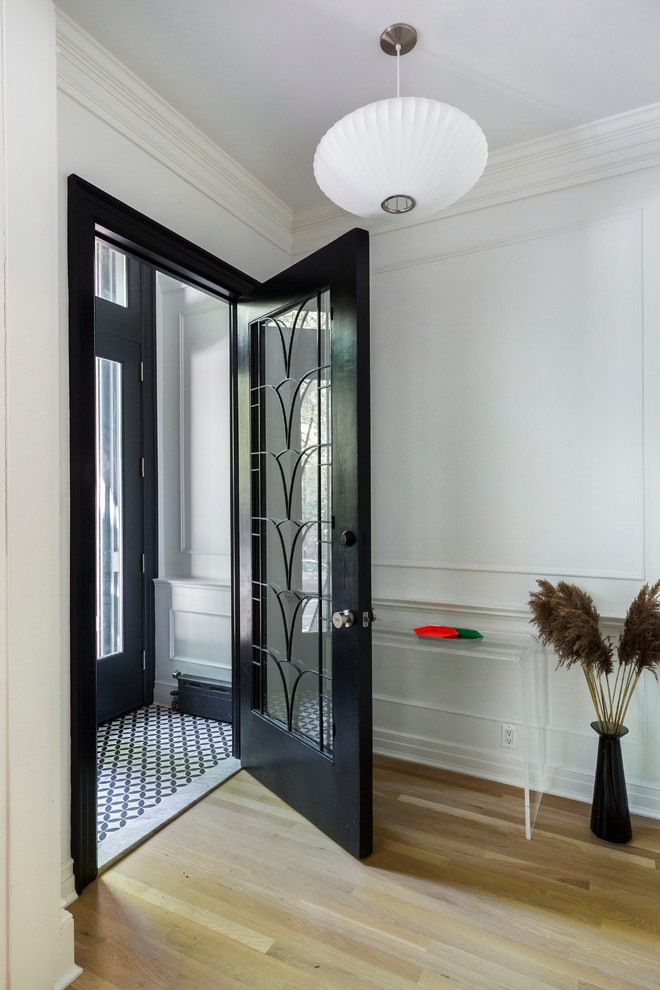 Diseño de vestíbulo tradicional renovado con paredes blancas, suelo de madera clara, puerta simple y puerta de vidrio
