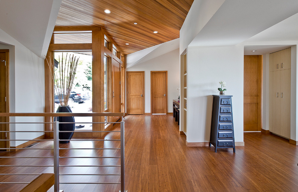 Idee per un grande ingresso contemporaneo con pareti bianche, pavimento in bambù, una porta singola e una porta in legno chiaro
