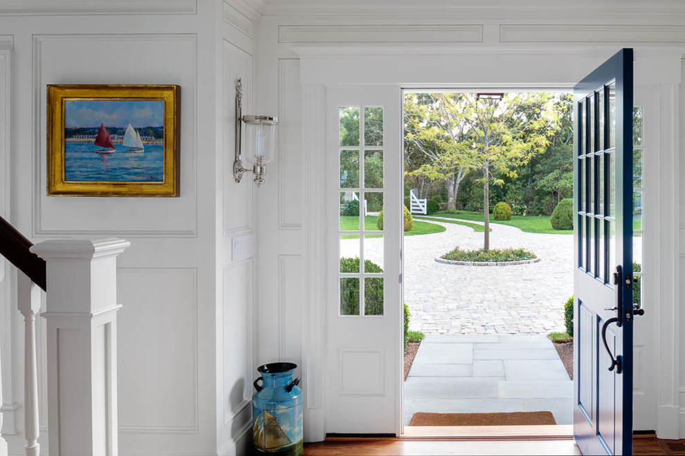 Idée de décoration pour un grand hall d'entrée marin avec un mur blanc, un sol en bois brun, une porte pivot et une porte bleue.
