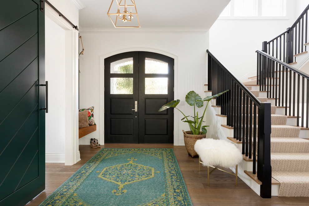 Immagine di un ingresso stile marino di medie dimensioni con pareti bianche, pavimento in legno massello medio, una porta a due ante e una porta nera