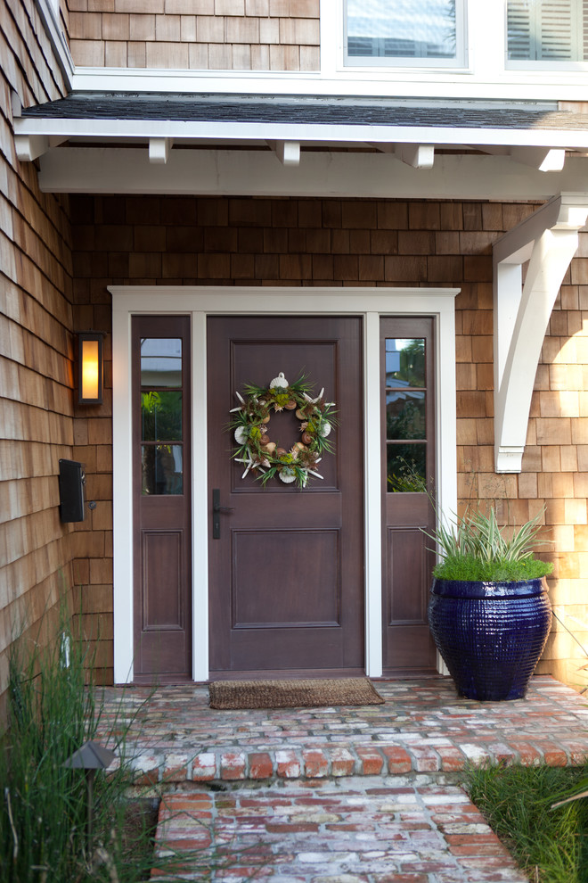 Ejemplo de puerta principal costera pequeña con paredes marrones, suelo de ladrillo, puerta simple y puerta marrón