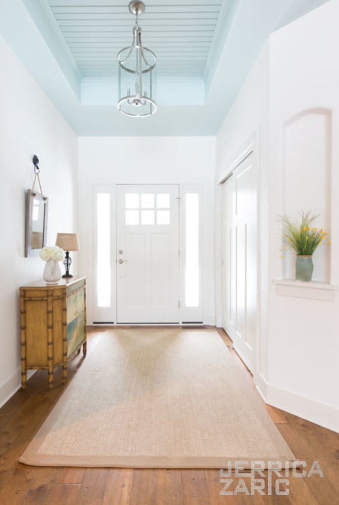 Idee per un grande ingresso stile marinaro con pareti bianche, pavimento in legno massello medio, una porta singola, una porta bianca e pavimento marrone