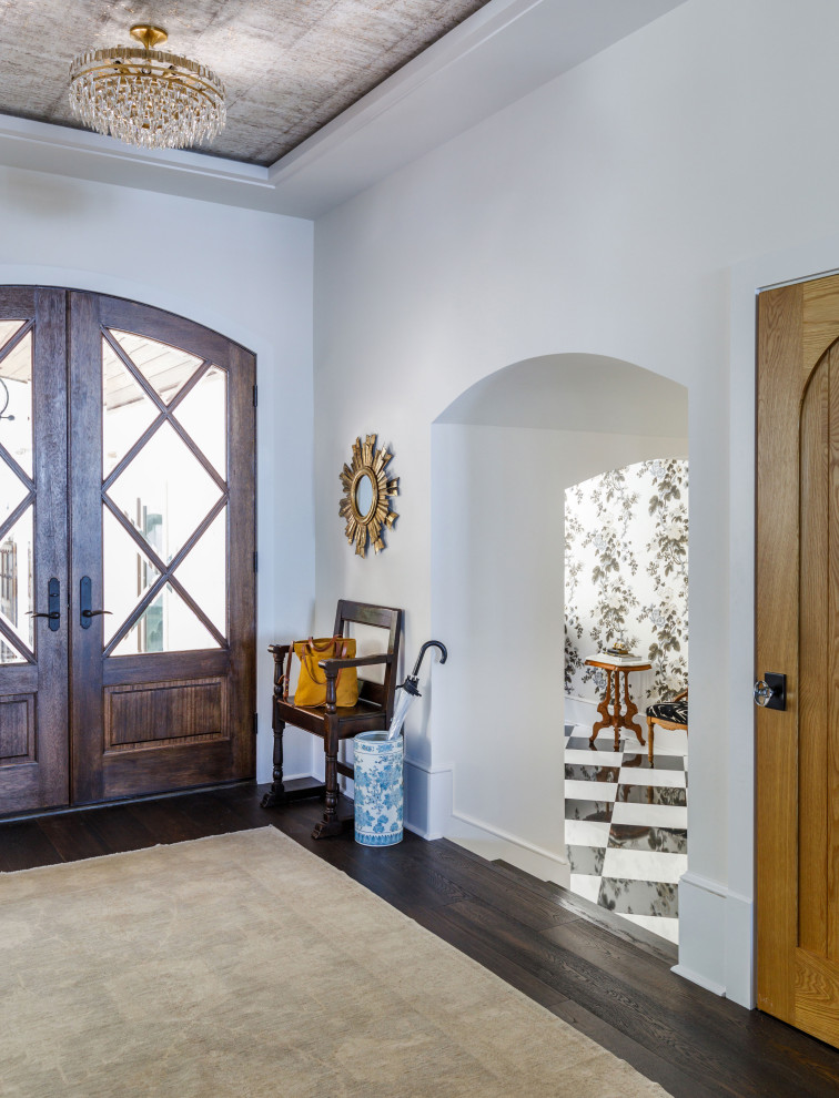 Example of a tuscan dark wood floor, brown floor and wallpaper ceiling entryway design in Jacksonville with white walls and a dark wood front door