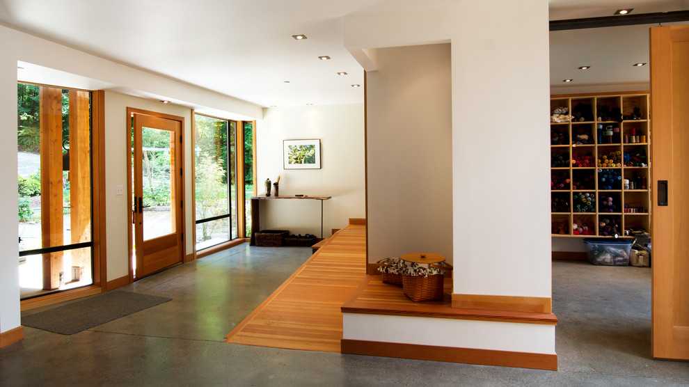 Foto de vestíbulo minimalista con paredes blancas, suelo de cemento, puerta simple y puerta de madera clara