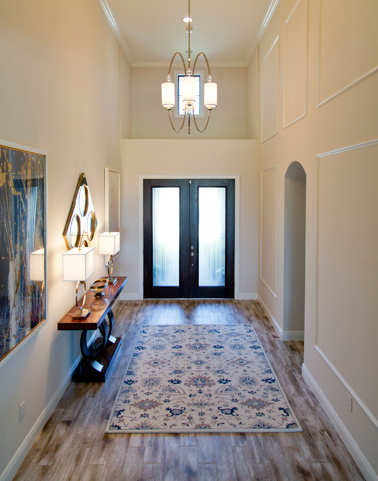 Entryway - large coastal medium tone wood floor and brown floor entryway idea in Miami with beige walls and a black front door
