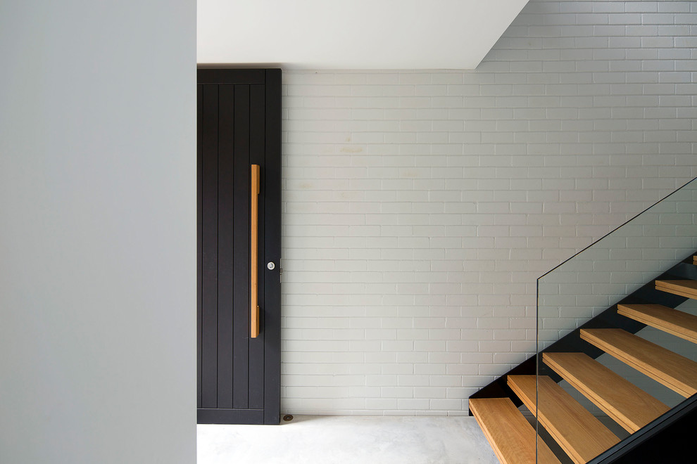 Ejemplo de distribuidor actual grande con paredes blancas, suelo de cemento, puerta simple, puerta negra y suelo gris