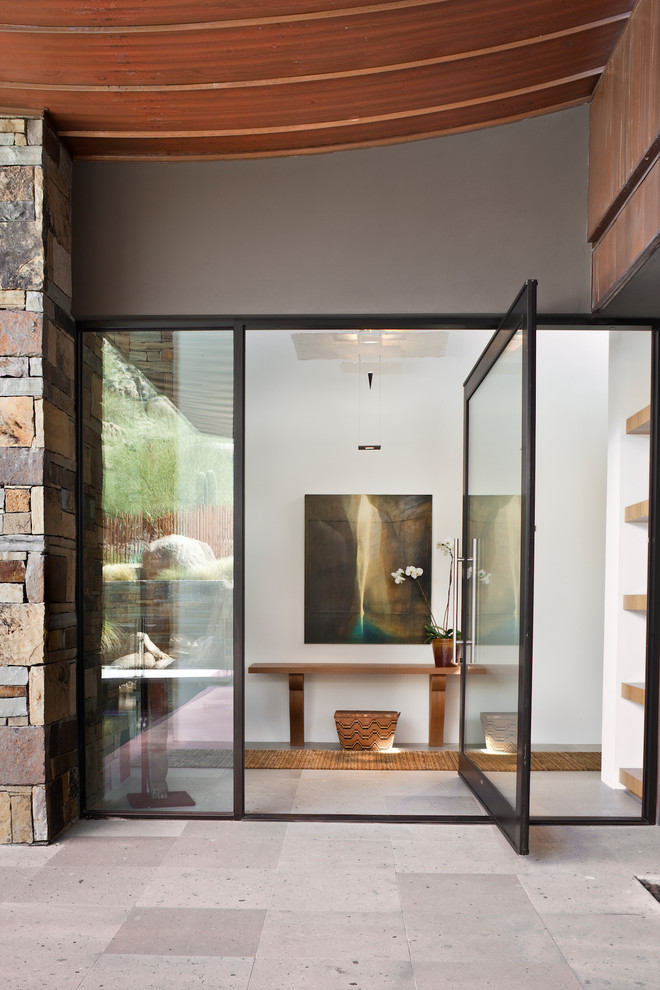 Idee per un'ampia porta d'ingresso minimalista con pareti bianche, una porta a pivot, una porta in vetro e pavimento grigio