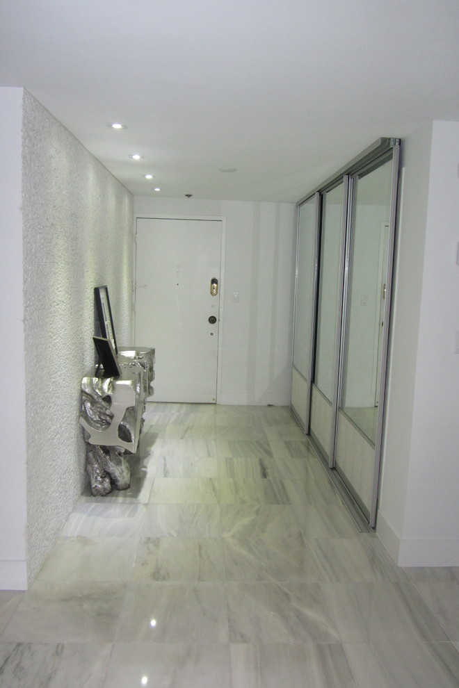 На фото: узкая прихожая среднего размера в современном стиле с белыми стенами, мраморным полом, одностворчатой входной дверью, белой входной дверью и серым полом