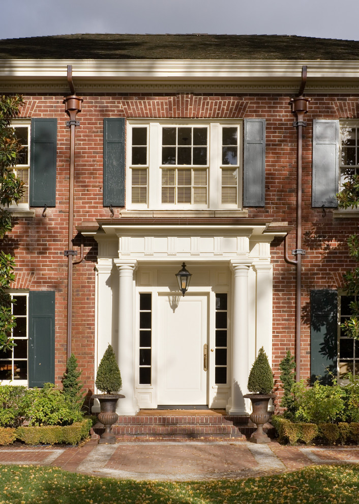 Стильный дизайн: входная дверь в классическом стиле с красными стенами, кирпичным полом, одностворчатой входной дверью, белой входной дверью и красным полом - последний тренд
