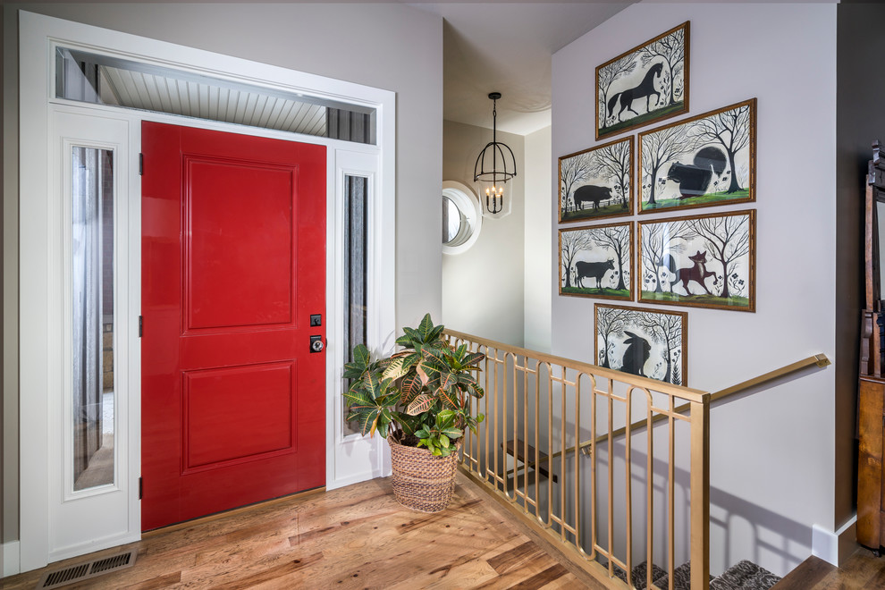Imagen de distribuidor tradicional pequeño con puerta simple, paredes grises, suelo de madera en tonos medios y puerta roja