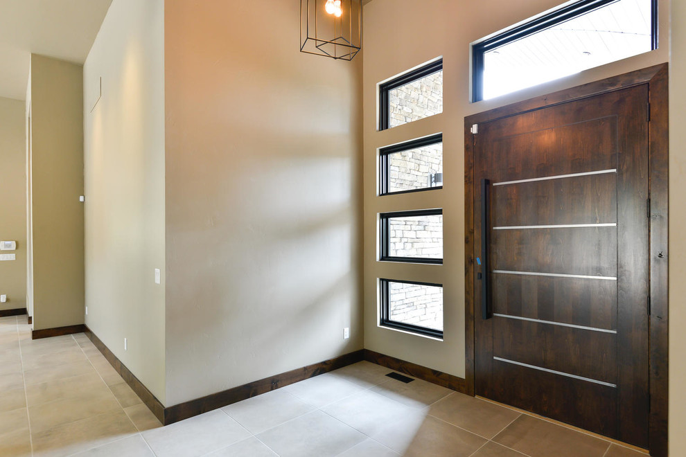 Aménagement d'une porte d'entrée contemporaine de taille moyenne avec un mur beige, un sol en carrelage de porcelaine, une porte simple, une porte en bois foncé et un sol beige.