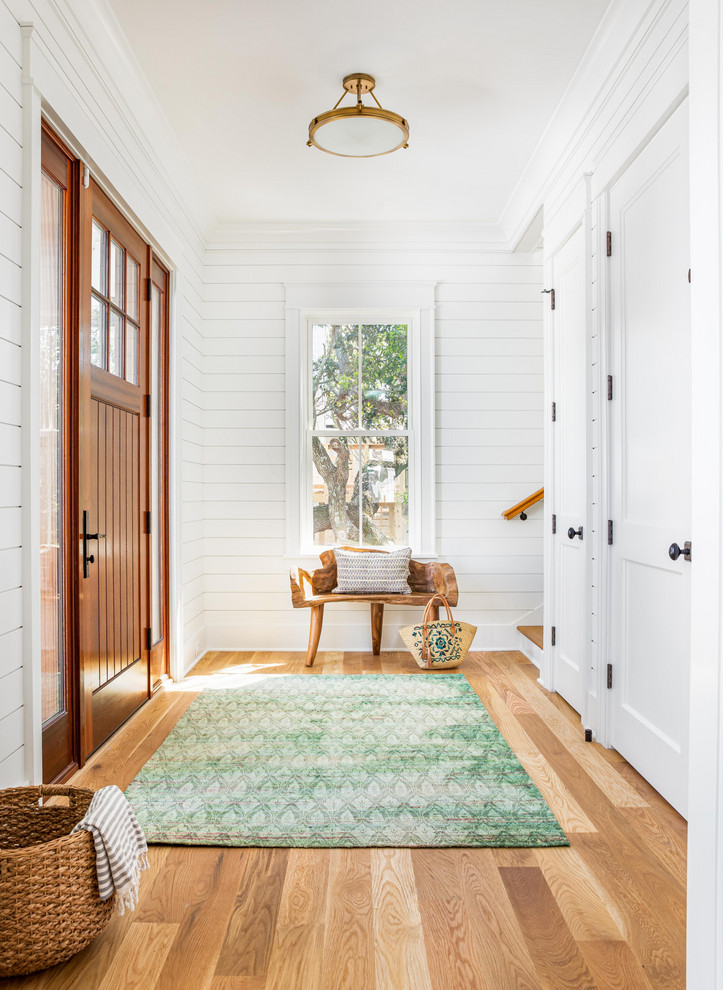 Maritimes Foyer mit weißer Wandfarbe, braunem Holzboden, Einzeltür, hellbrauner Holzhaustür und braunem Boden in Charleston
