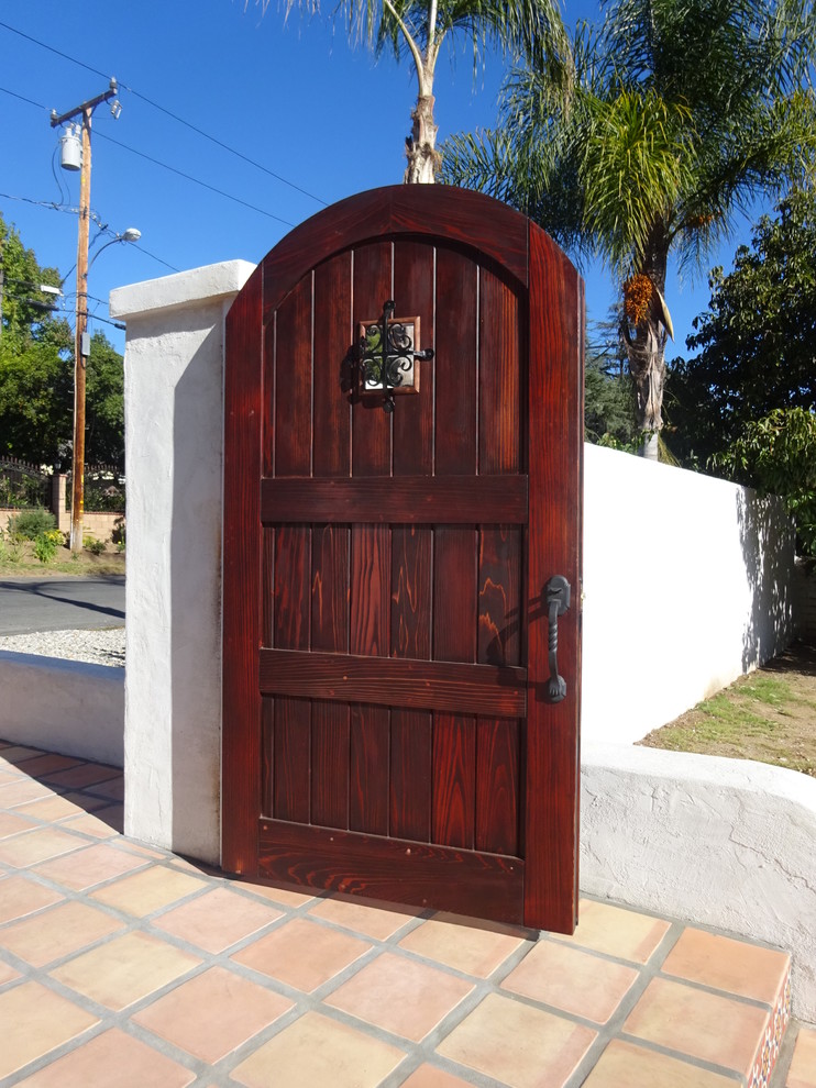 На фото: входная дверь среднего размера в средиземноморском стиле с белыми стенами, полом из терракотовой плитки, одностворчатой входной дверью и входной дверью из темного дерева