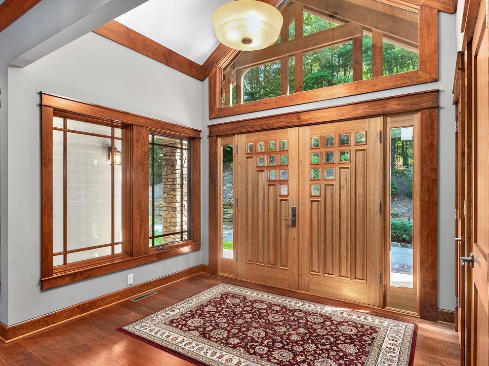 Diseño de distribuidor rústico de tamaño medio con paredes grises, suelo de madera en tonos medios, puerta doble, puerta de madera clara y suelo marrón