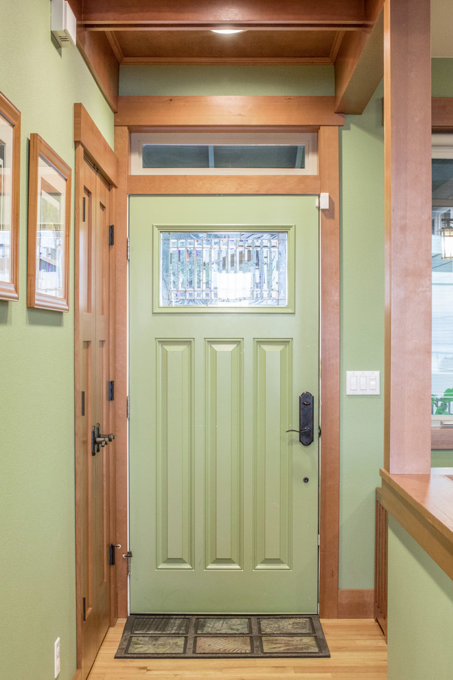 Inspiration för mellanstora amerikanska hallar, med gröna väggar, ljust trägolv, en enkeldörr och en grön dörr