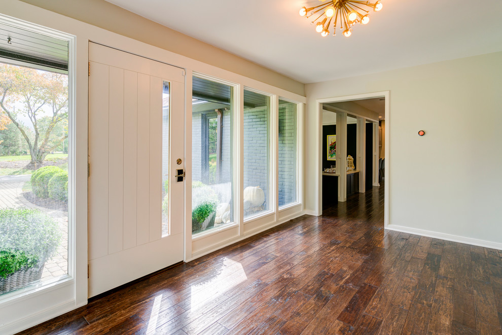 Ejemplo de puerta principal contemporánea grande con paredes grises, suelo de madera en tonos medios, puerta simple y puerta blanca