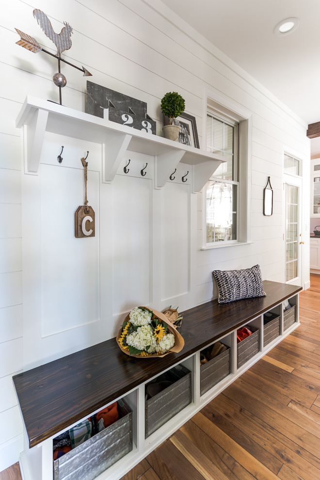 Farmhouse medium tone wood floor and brown floor mudroom photo in Raleigh with white walls