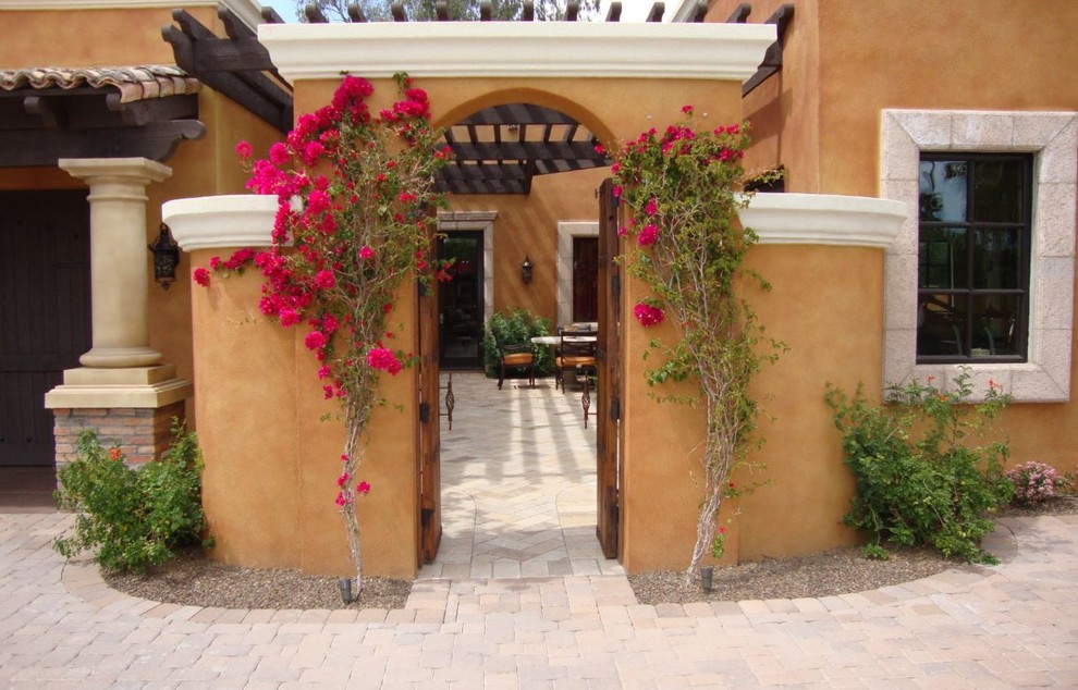 Ejemplo de puerta principal mediterránea de tamaño medio con paredes marrones, suelo de ladrillo, puerta doble, puerta de madera en tonos medios y suelo rojo