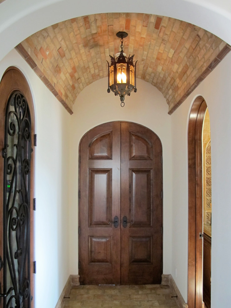 Пример оригинального дизайна: маленькая входная дверь в средиземноморском стиле с белыми стенами, двустворчатой входной дверью и входной дверью из темного дерева для на участке и в саду