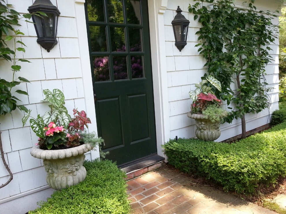 Aménagement d'une porte d'entrée classique de taille moyenne avec un mur blanc, un sol en brique, une porte simple et une porte verte.