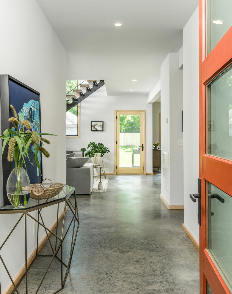 Esempio di un piccolo corridoio contemporaneo con pareti bianche, pavimento in cemento, una porta singola, una porta arancione e pavimento grigio