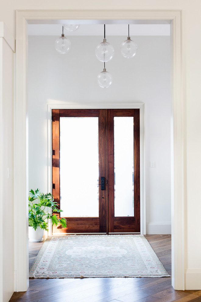 Inspiration for a large farmhouse foyer in Toronto with white walls, medium hardwood flooring, a single front door and a dark wood front door.