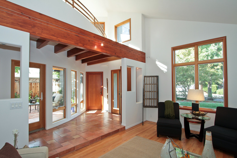 Réalisation d'une entrée design de taille moyenne avec un couloir, un mur blanc, un sol en carrelage de céramique, une porte simple, une porte en bois brun et un sol rouge.