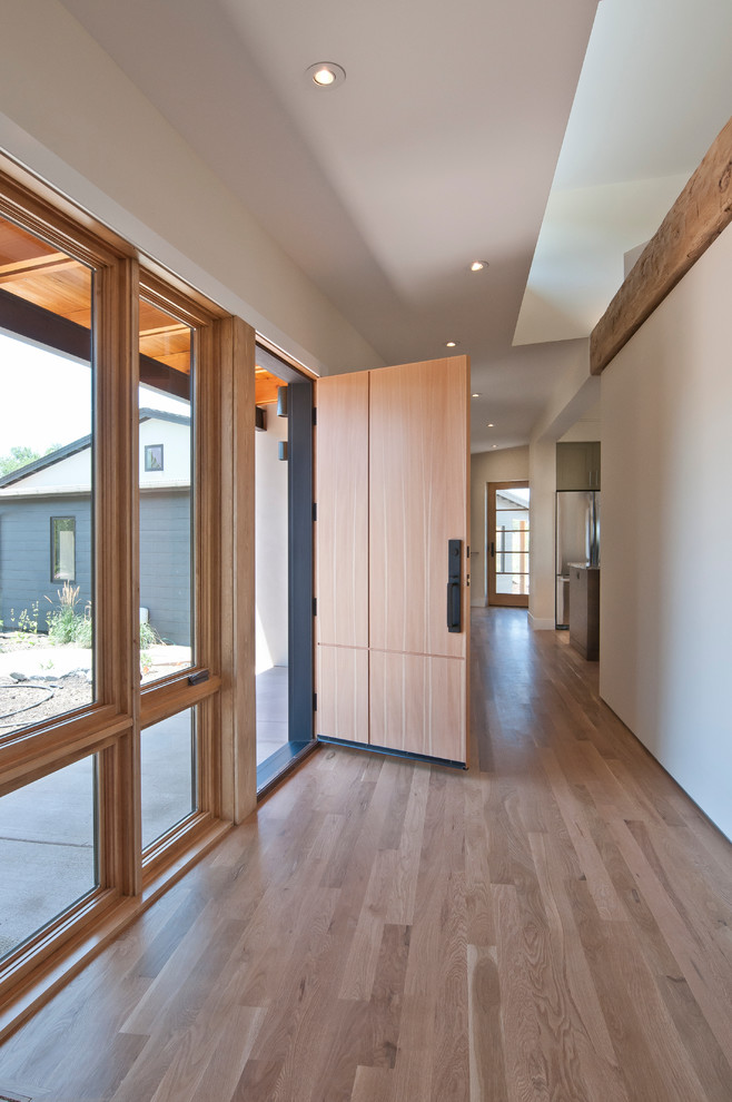 Источник вдохновения для домашнего уюта: узкая прихожая среднего размера в современном стиле с входной дверью из светлого дерева, белыми стенами, светлым паркетным полом и одностворчатой входной дверью