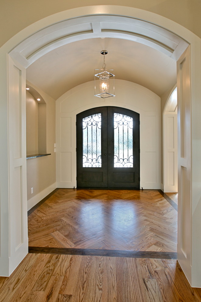 Réalisation d'un grand hall d'entrée design avec un mur blanc, un sol en bois brun, une porte double et une porte noire.