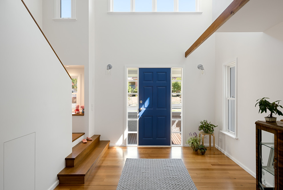 This is an example of a contemporary foyer in Melbourne with white walls, medium hardwood flooring, a single front door and a blue front door.