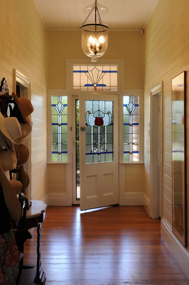 Cette photo montre une entrée victorienne avec un couloir, un sol en bois brun, une porte simple et une porte en verre.