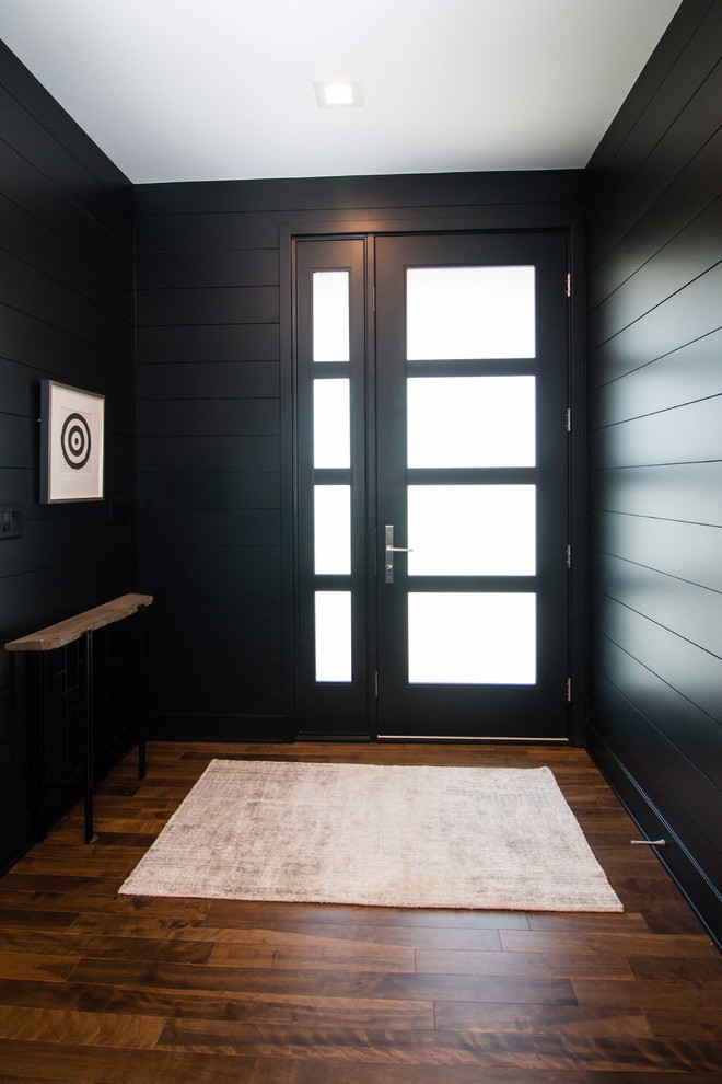 Cette photo montre une porte d'entrée moderne de taille moyenne avec un mur noir, parquet foncé, une porte simple, une porte en verre et un sol marron.