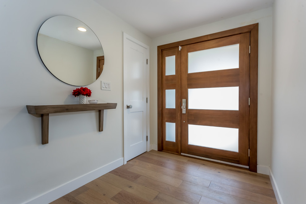 Modelo de puerta principal contemporánea de tamaño medio con paredes blancas, suelo de madera en tonos medios, puerta simple, puerta de madera en tonos medios y suelo marrón