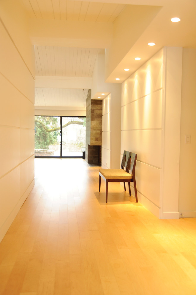 Aménagement d'une grande entrée contemporaine avec un couloir, un mur blanc et parquet clair.