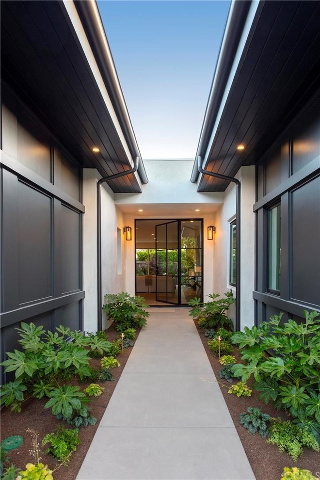 Großes Modernes Foyer mit schwarzer Wandfarbe, Betonboden, Drehtür, Haustür aus Metall und grauem Boden in Orange County