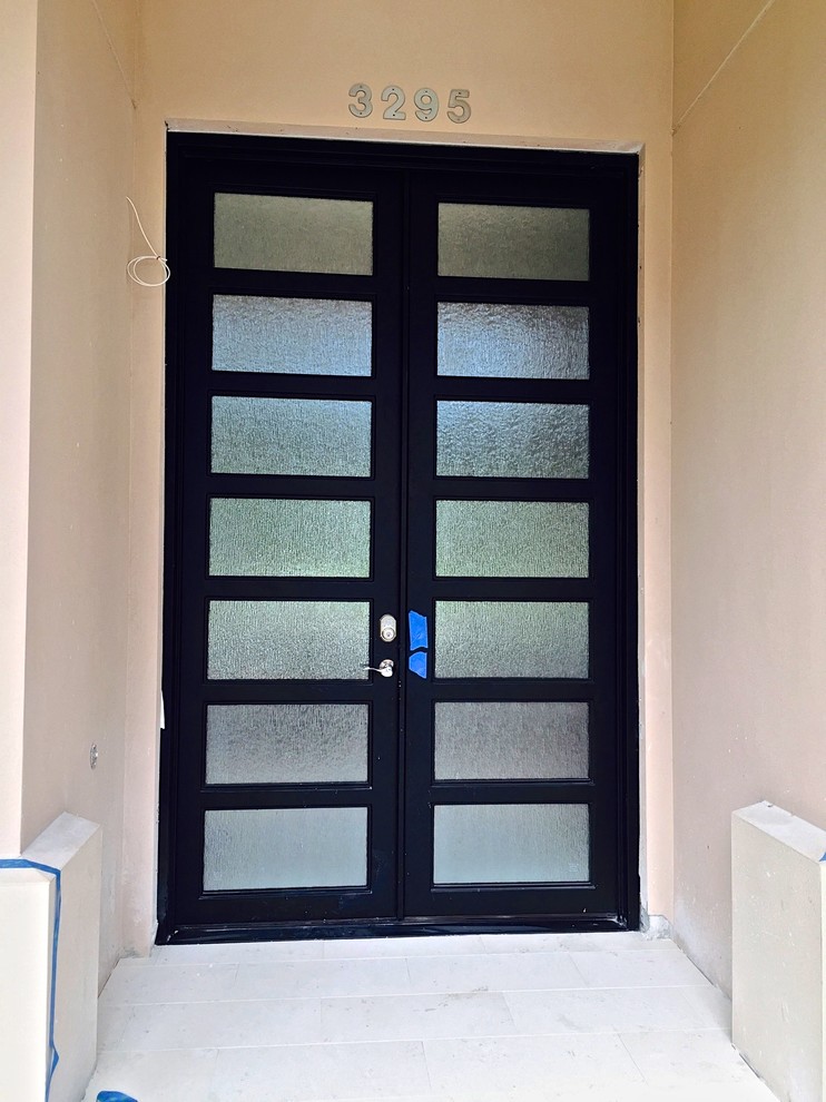 Réalisation d'une grande porte d'entrée design avec une porte double et une porte métallisée.