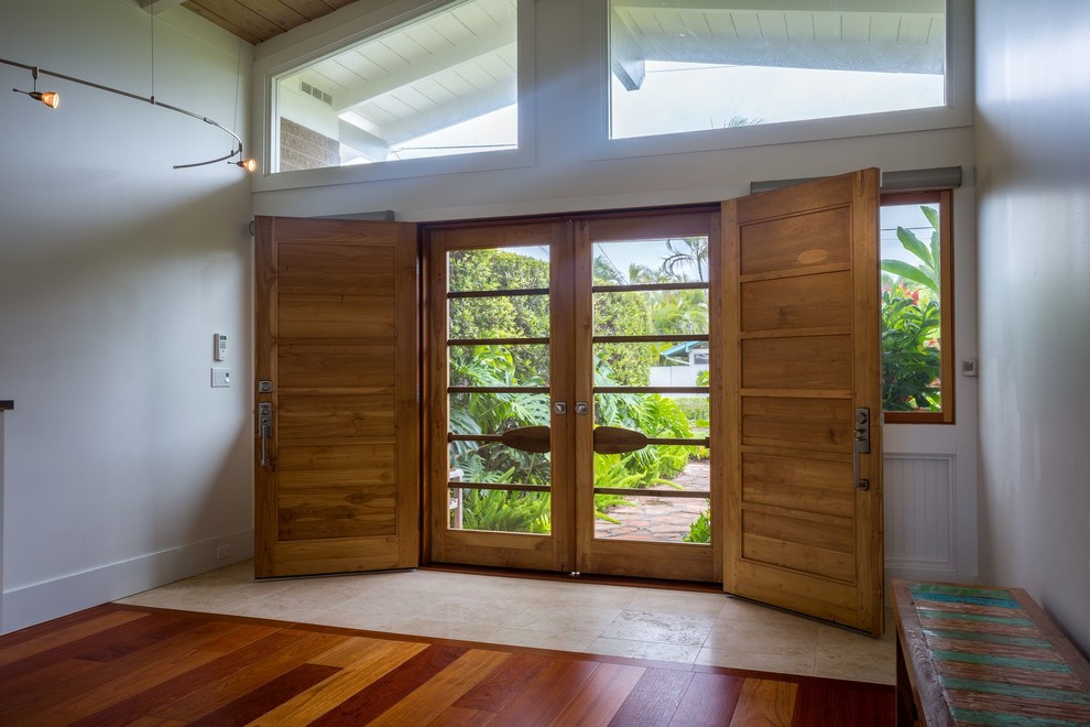 Ejemplo de puerta principal tropical grande con paredes blancas, suelo de madera en tonos medios, puerta doble, puerta de vidrio y suelo marrón
