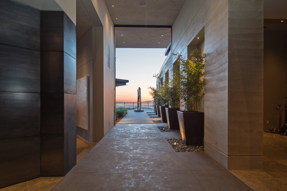 Idee per un ampio ingresso moderno con pareti beige, pavimento in cemento e una porta in legno bruno