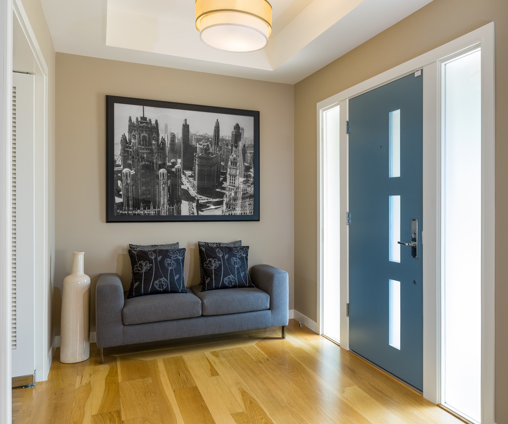 Ispirazione per un corridoio moderno di medie dimensioni con pareti beige, parquet chiaro, una porta singola e una porta blu