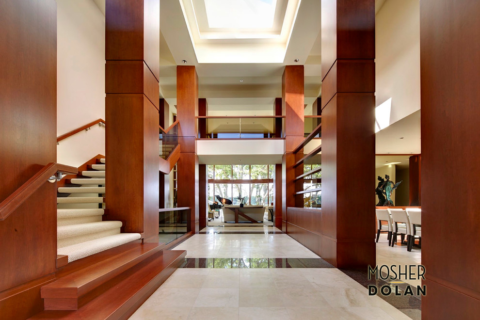 Cette image montre une très grande entrée design avec un couloir, un mur blanc et un sol en marbre.