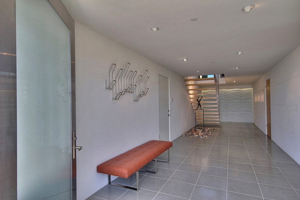 На фото: большая прихожая в современном стиле с белыми стенами, полом из керамической плитки, поворотной входной дверью и металлической входной дверью