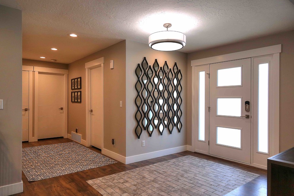 ソルトレイクシティにある高級な中くらいなコンテンポラリースタイルのおしゃれな玄関ロビー (グレーの壁、ラミネートの床、白いドア、茶色い床) の写真