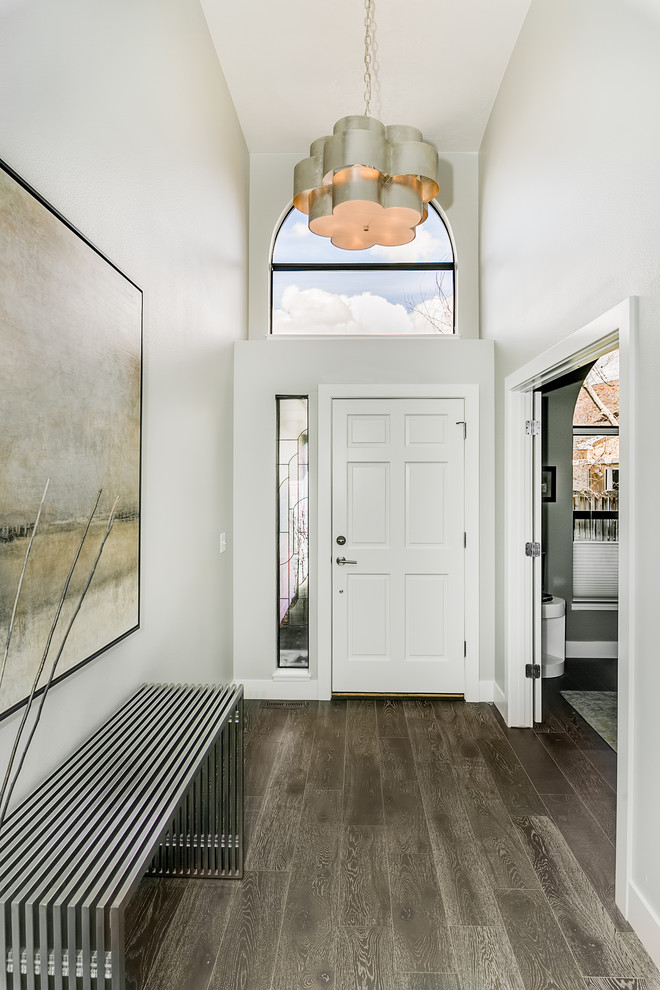 Cette image montre un hall d'entrée design de taille moyenne avec un mur gris, parquet foncé, une porte simple, une porte blanche et un sol gris.